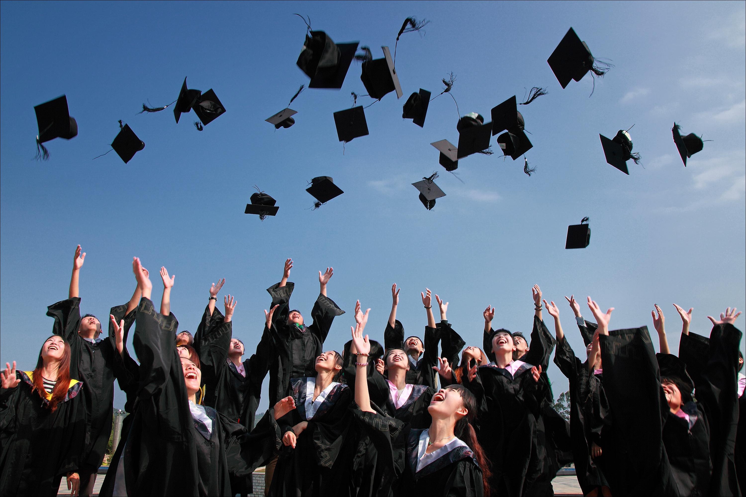 graduation party throwing graduation caps in the air outside